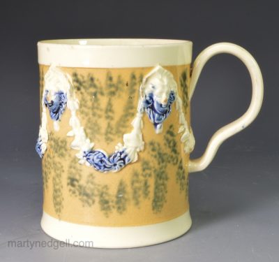 Creamware pottery mug decorated with tan slip and blue sponging, circa 1790