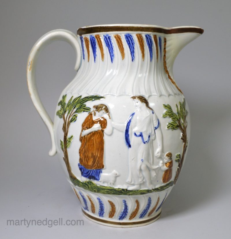Prattware pottery jug moulded with Offerings to Peace and grooms drinking and decorated with high fired enamels under a pearlware glaze, circa 1800