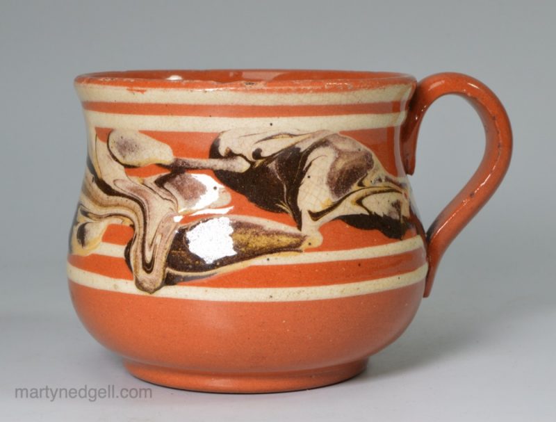 Small mocha ware mug decorated with snail trail on a brown body, circa 1820