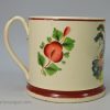 Creamware pottery mug decorated with a coloured print of a drinking scene, circa 1820
