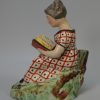 Staffordshire pearlware pottery figure of a girl reading, circa 1820