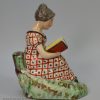 Staffordshire pearlware pottery figure of a girl reading, circa 1820