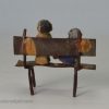 Toy soft metal golly and doll on a bench, circa 1900