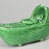 Green glazed creamware pottery toy cradle and sleeping child, circa 1820