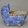 Prattware pottery toy baby in a cradle, circa 1820, probably Bovey Tracey Pottery