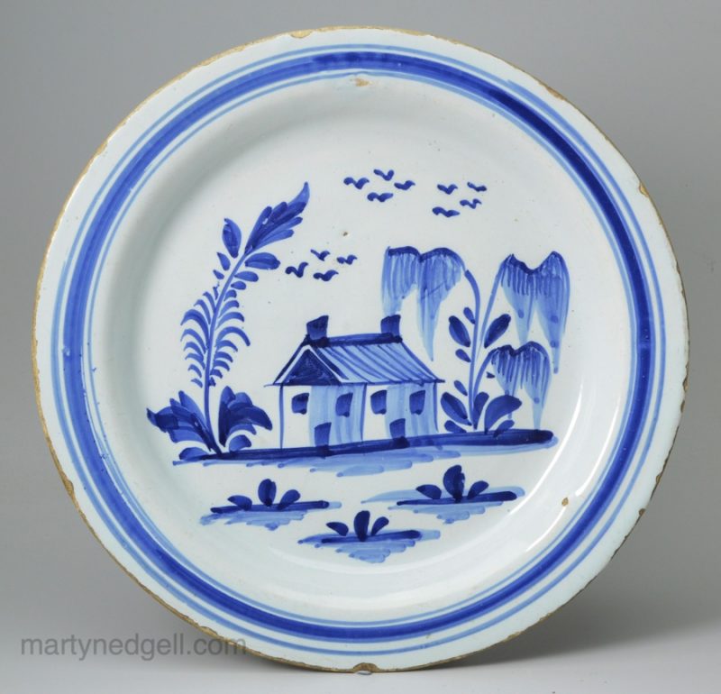 London delft plate painted in blue with a naive house, circa 1720