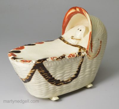 Bovey Tracey creamware pottery model of a cradle with a young child, circa 1800