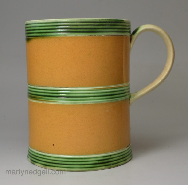 Creamware pottery mug decorated with tan slip and green glaze, circa 1800