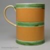 Creamware pottery mug decorated with tan slip and green glaze, circa 1800