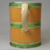 Creamware pottery mug decorated with tan slip and green glaze, circa 1800