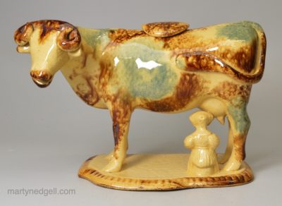 Buff coloured pottery cow creamer decorated with colours under the glaze, circa 1860