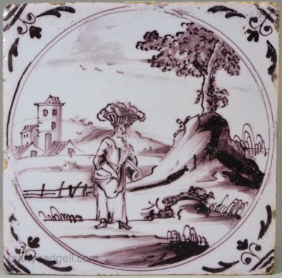 London delft tile decorated in manganese with a woman carrying a basket on her head, circa 1740