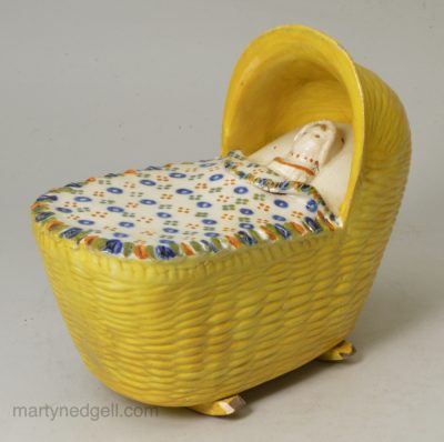 Prattware pottery child in a cradle, circa 1820, possibly Bovey Tracey Pottery Devon