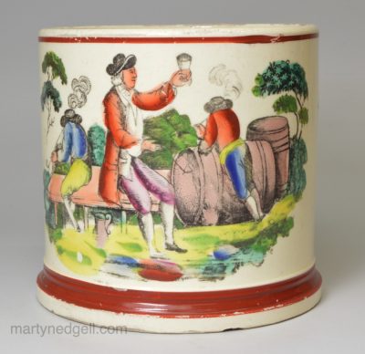 Creamware pottery mug decorated with a print of a drinking scene and coloured over the glaze, circa 1820