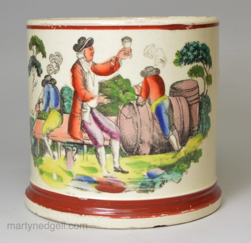 Creamware pottery mug decorated with a print of a drinking scene and coloured over the glaze, circa 1820