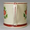 Creamware pottery mug decorated with a print of a drinking scene and coloured over the glaze, circa 1820