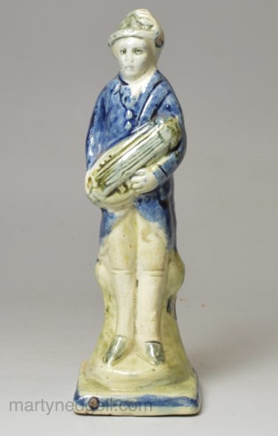 Pearlware pottery figure of a man playing the hardy curdy decorated with colours under the glaze, circa 1800