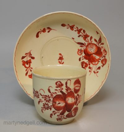 Creamware pottery coffee cup and saucer painted with red enamels over the glaze, circa 1770, probably Leeds Pottery