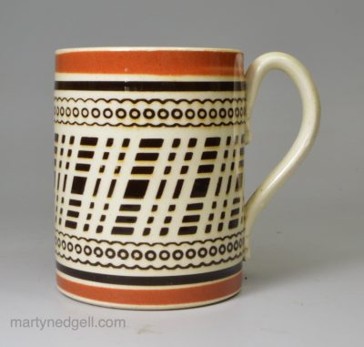 Mochaware mug decorated with inlaid brown slip on a creamware pottery body, circa 1820