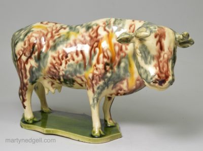 Creamware pottery cow decorated with underglaze oxides and green glazed slab base, circa 1765