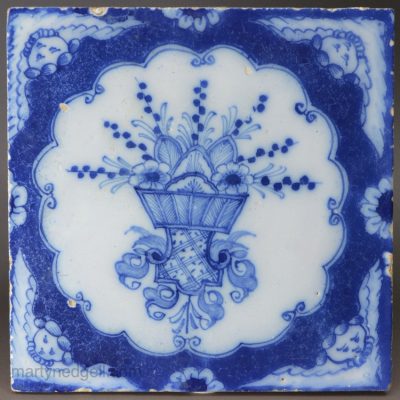 Liverpool delft tile decorated with angel head corners and floral arrangement, circa 1750