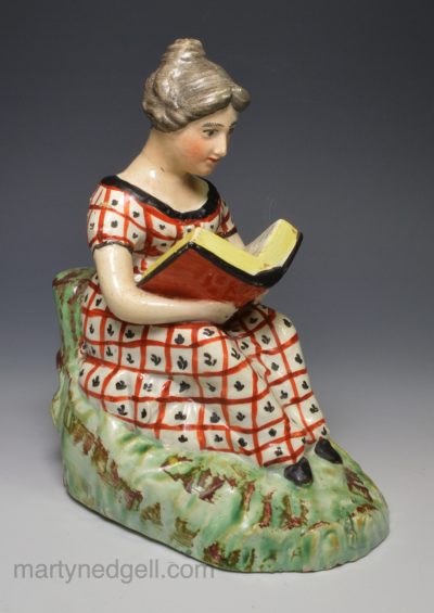 Staffordshire pearlware pottery figure of a girl reading, circa 1820