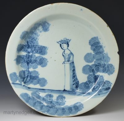 London delft pancake plate decorated with a girl and basket on her head, circa 1740