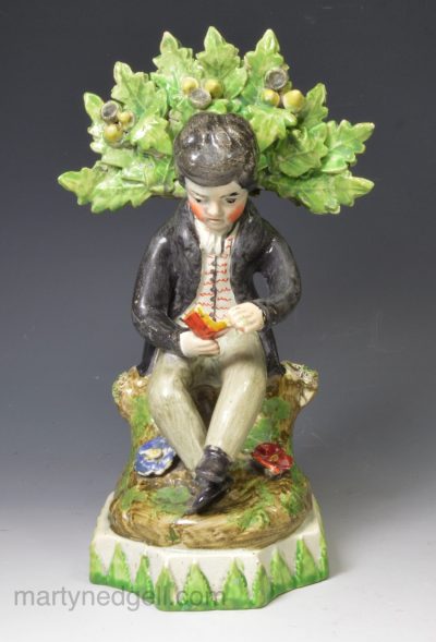Staffordshire pearlware pottery bocage figure of a boy reading, circa 1820