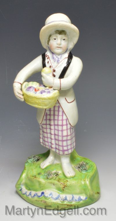 Staffordshire pearlware pottery figure of a girl carrying a fruit basket, circa 1820