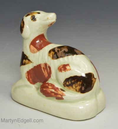 Creamware pottery spaniel decorated with dawbs of coloured slip, circa 1800, Probably Bovey Tracey Pottery