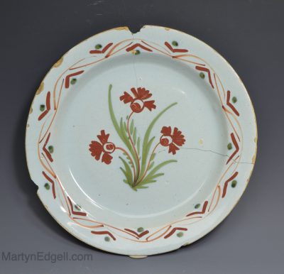 London delft pancake plate decorated with red, orange and green florals, circa 1740
