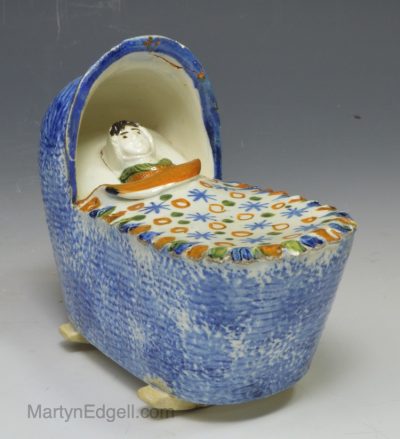 Prattware pottery child's toy cradle and baby, circa 1820, possibly Bovey Tracy