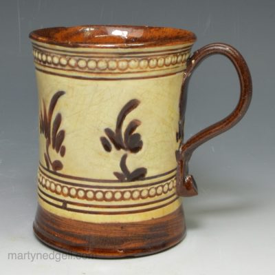 Staffordshire brown agate mug decorated with cream slip that has been carved away, circa 1750