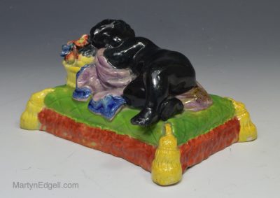 Staffordshire pearlware pottery figure of a child asleep on a basket of fruit, circa 1820