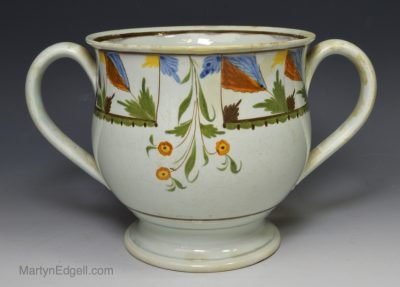 Large prattware pottery loving cup decorated with colours under the glaze, circa 1820