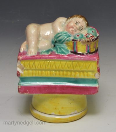 Pearlware pottery snuff box moulded with a baby sleeping on a fruit basket, circa 1820